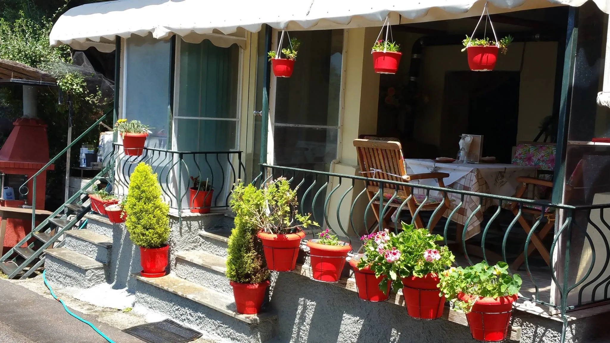 Η είσοδος της ταβέρνας με τις κόκκινες γλάστρες και τα λουλούδια